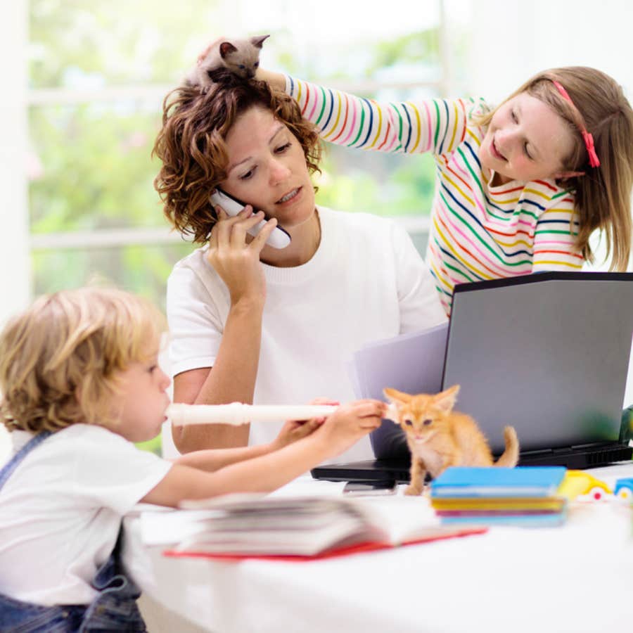 girl playing with mom's hair while she's on the phone and working